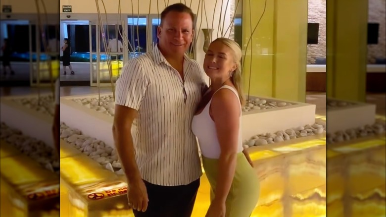 Nicholas Riccio and Karoline Leavitt smiling and posing together in a hotel lobby