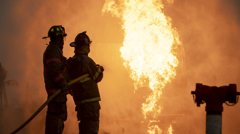 Firefighters holding fire extinguisher and pointing at a house fire