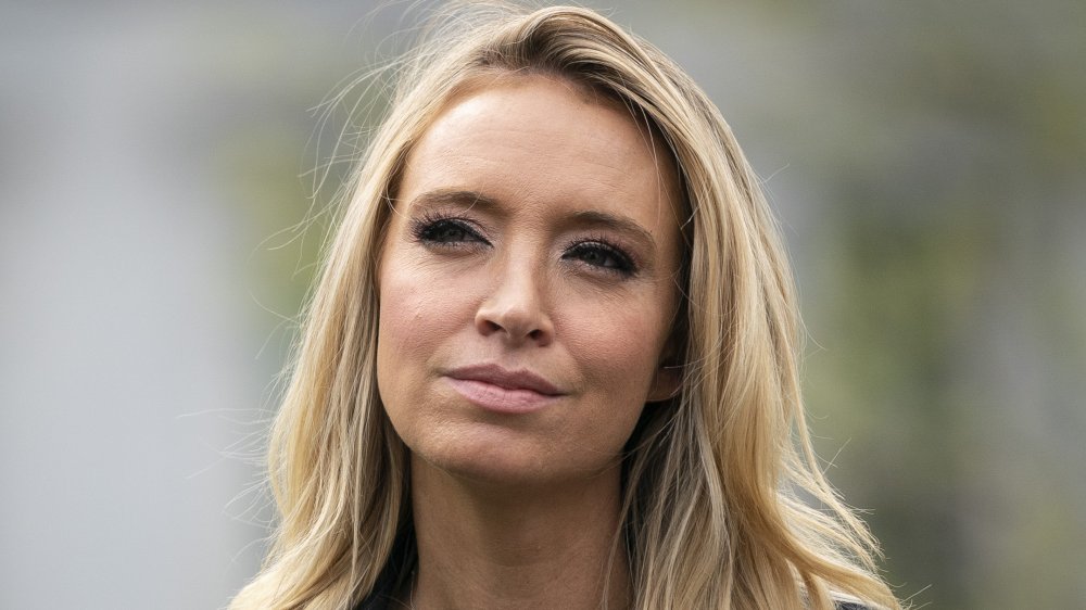 Kayleigh McEnany in a black jacket, squinting outside while looking off to the side