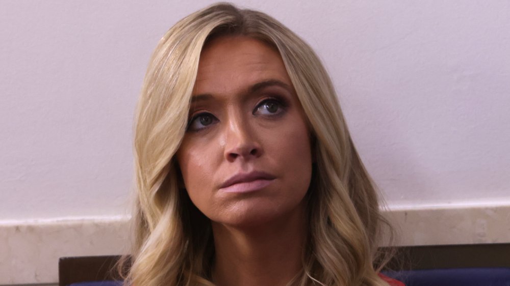 Kayleigh McEnany in a red dress, tilting her head with a serious expression