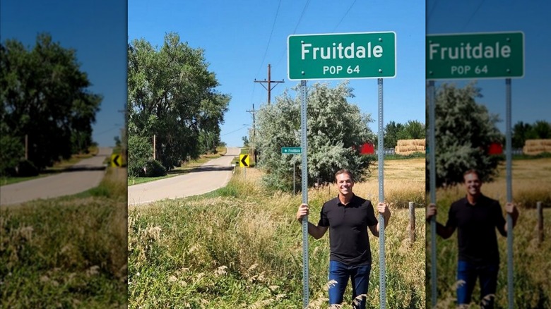 Bryon Noem posing with "Fruitdale Pop 64" road sign