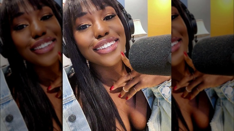 Laci Mosley, smiling, selfie, wearing headphones, near a podcast microphone