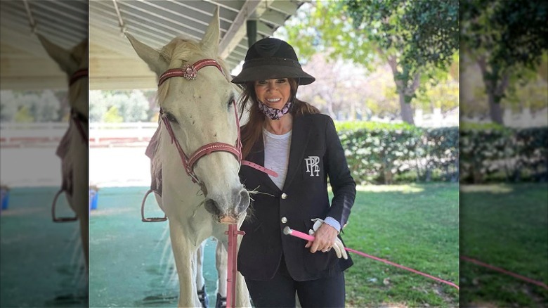 Lisa Vanderpump posing and smiling with a horse