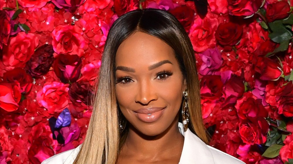 Malika Haqq smiling in front of a rose wall