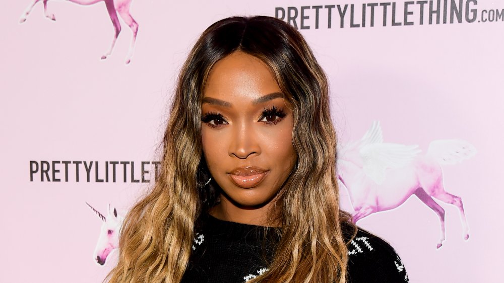 Malika Haqq in front of a Pretty Little Thing promotional wall
