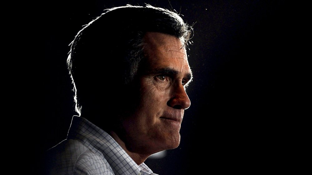 Mitt Romney looking somber in dim light 