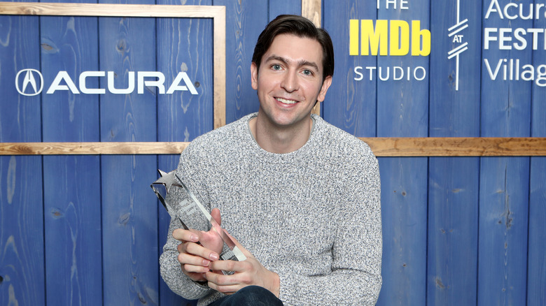 Nicholas Braun posing with award