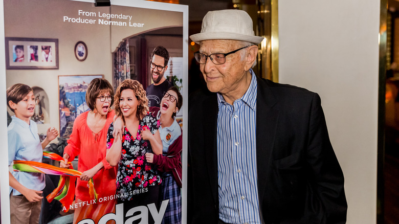 Norman Lear posing with poster for One Day at a Time