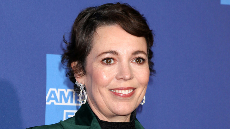 Olivia Colman smiling in a green jacket