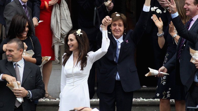 Paul McCartney and Nancy Shevell, both smiling with hands in air