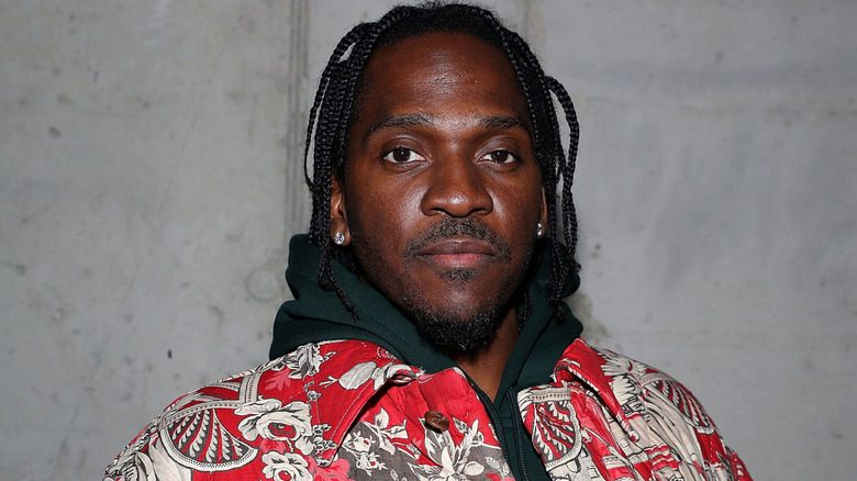 Pusha T wearing a red jacket, posing