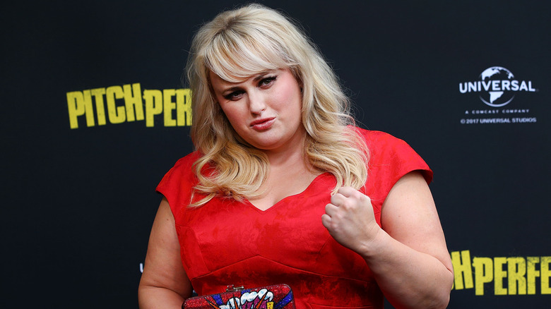 Rebel Wilson wearing a red dress on a red carpet