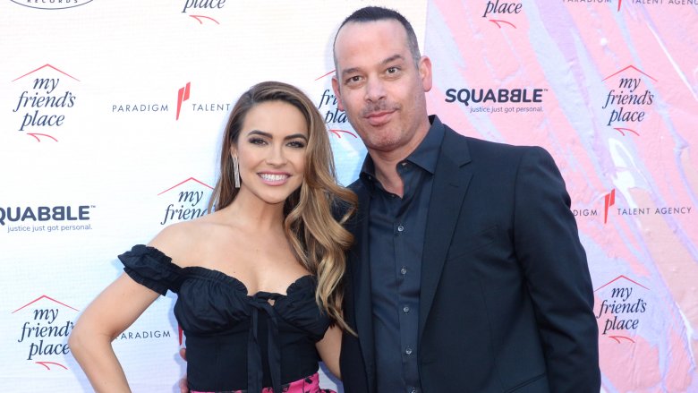Chrishell Stause in a black-and-pink dress, Adam DiVello in a blue shirt and blazer
