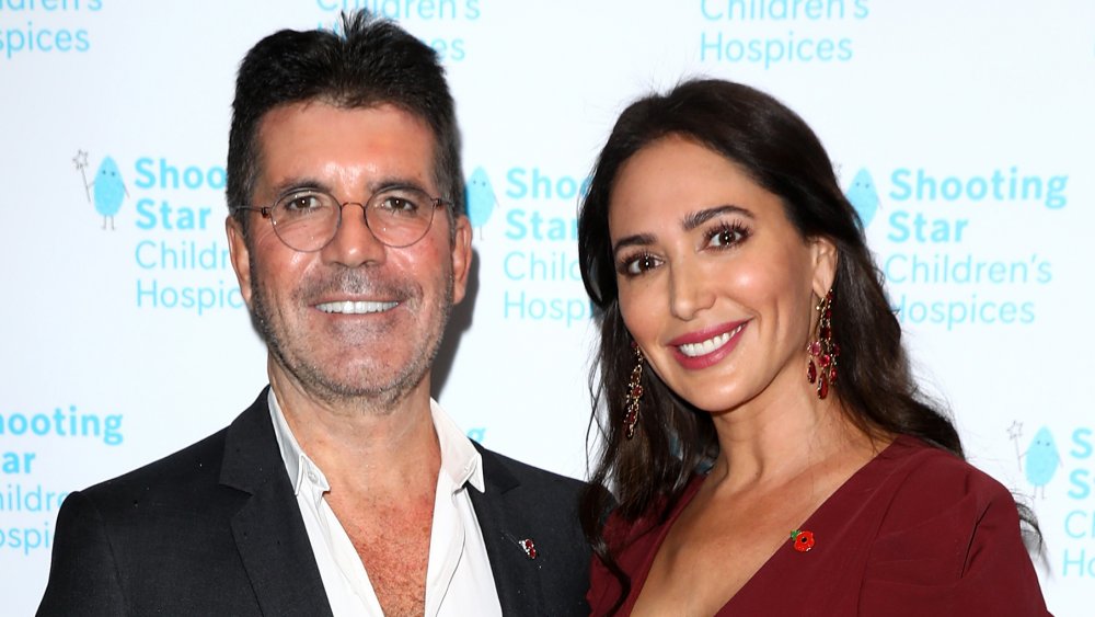 Simon Cowell and Lauren Silverman, smiling while posing arm in arm