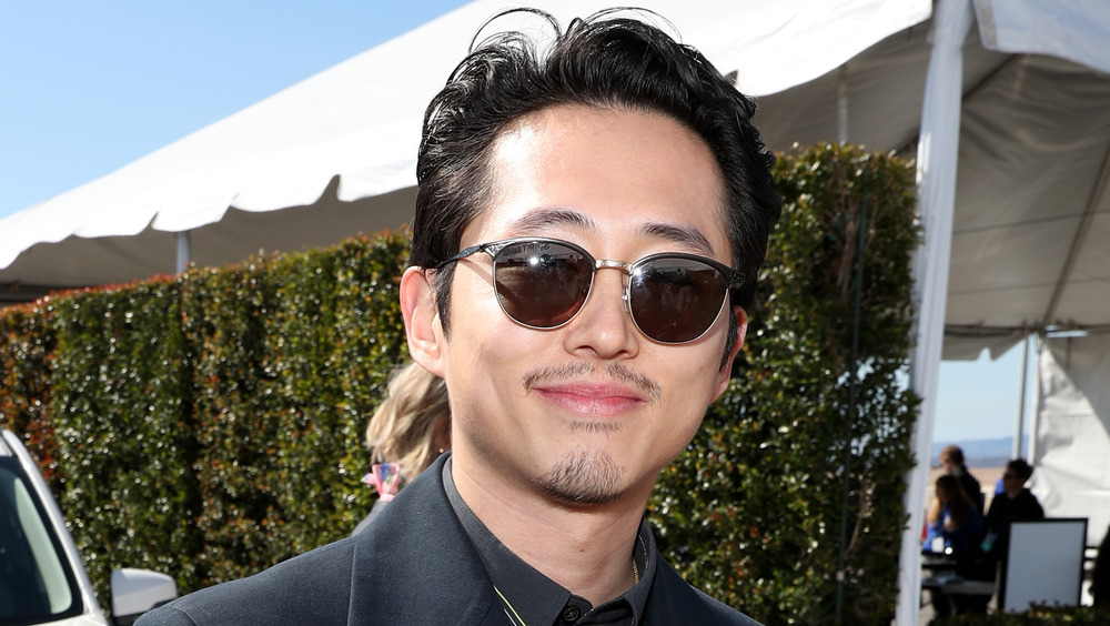 Steven Yeun smiling in sunglasses
