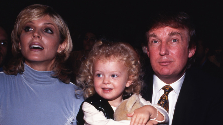 Marla Maples and Donald Trump smiling and sitting with young daughter Tiffany Trump
