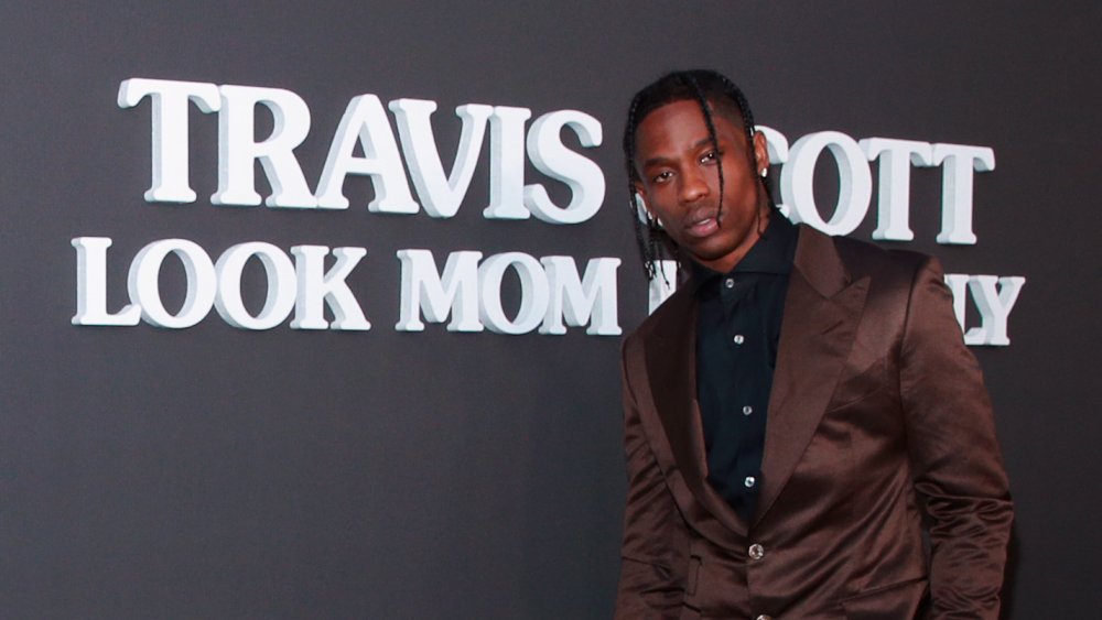 Travis Scott posing in front of his album title 