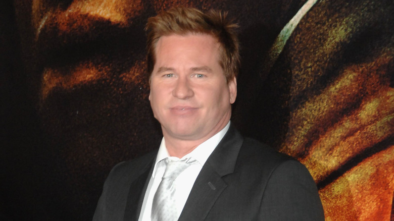 Val Kilmer, smiling and striking a pose at a movie premiere