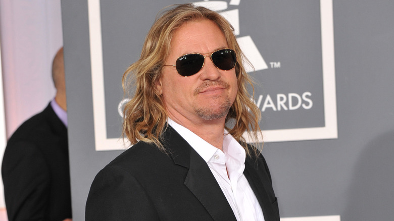 Val Kilmer, smiling while posing at an event