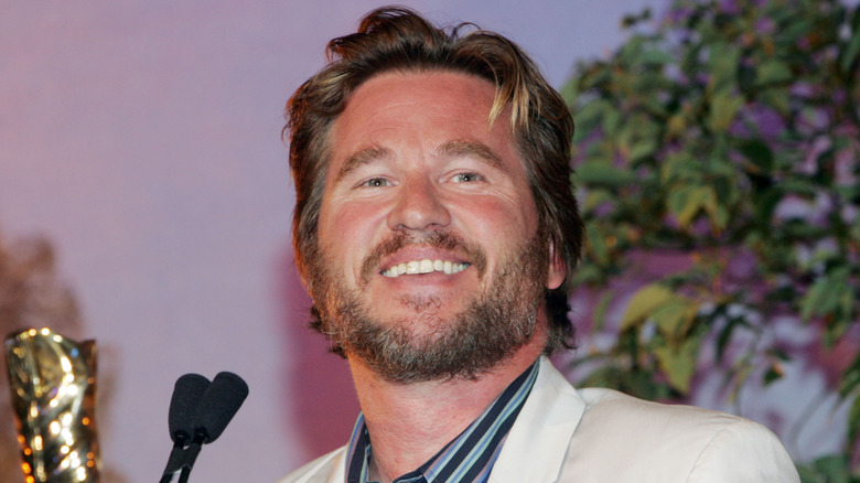 Val Kilmer smiling on stage