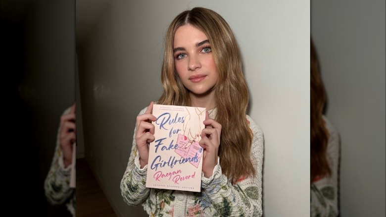 Raegan Revord displaying a copy of their book