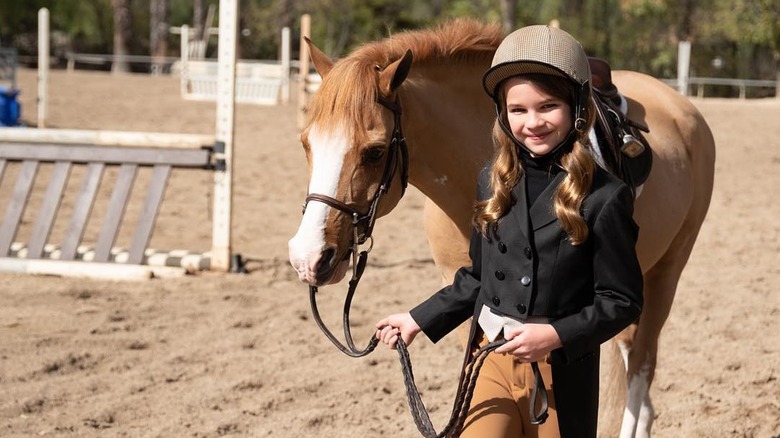 Raegan Revord as a child, posing with a horse