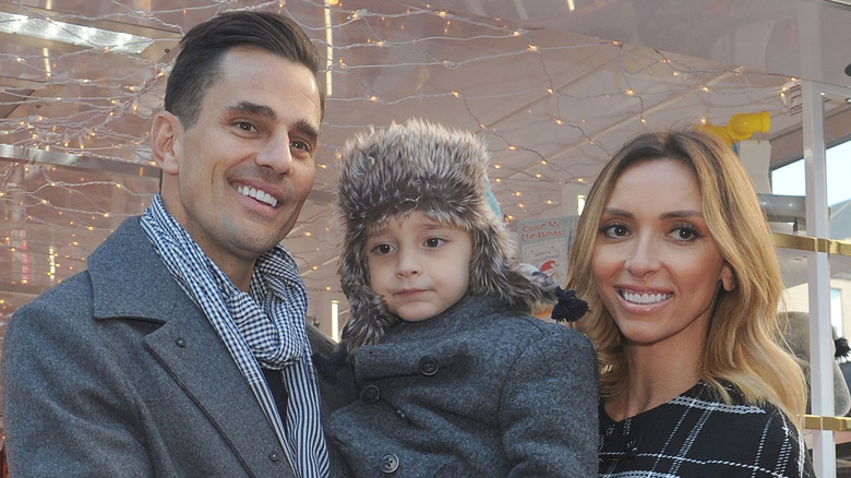 Bill Rancic and Giuliana Rancic smile as they hold a young Duke Rancic.