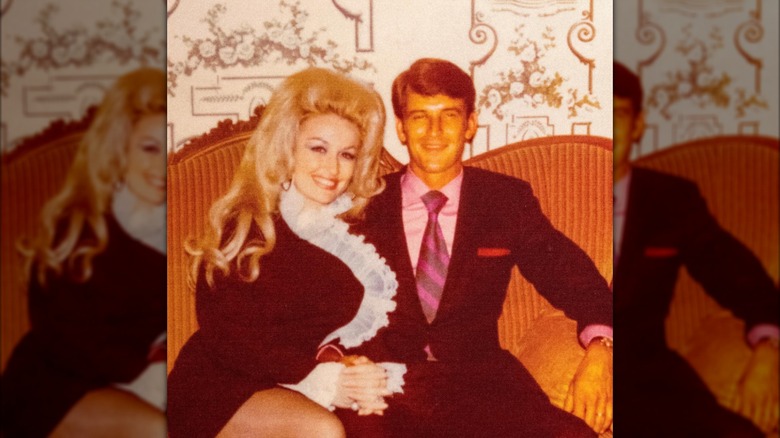 Dolly Parton and Carl Dean posing together on a sofa.