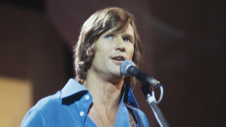 Kris Kristofferson gazes upward while singing into a microphone.