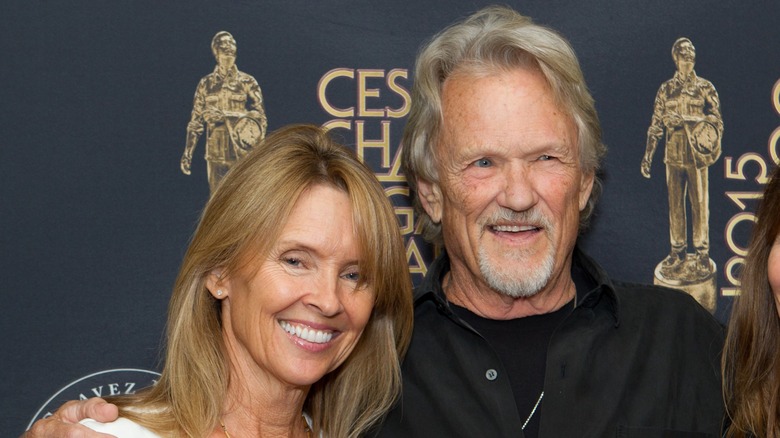 Tracy Kristofferson flashes a wide smile as Kris Kristofferson's arm is wrapped around her.