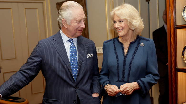 King Charles and Queen Camilla smile at one another.