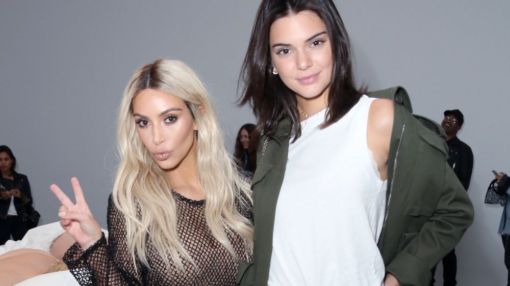 Kim Kardashian flashing a piece sign with Kendall Jenner at a fashion show