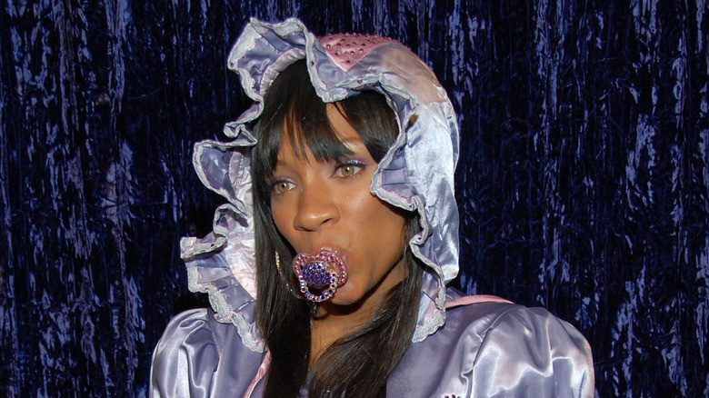 Lil Mama wearing a lilac silk bonnet and dress with a diamond-encrusted pacifier.
