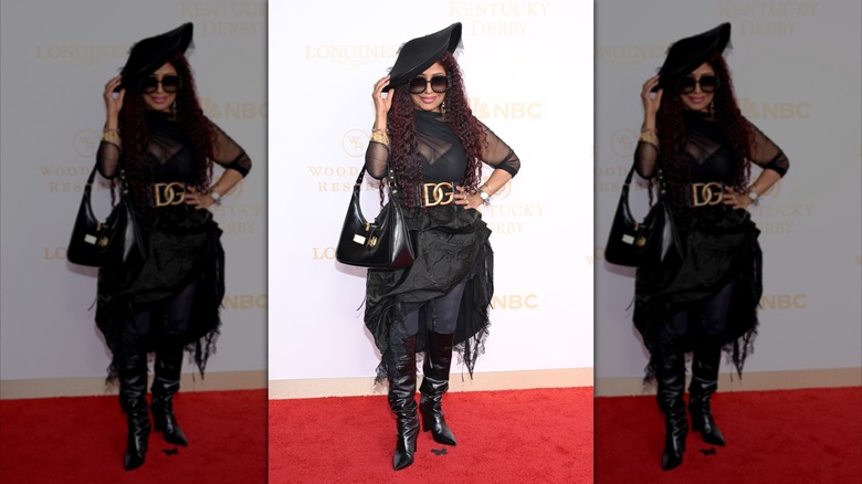 Chaka Khan posing in all-black outfit with knee-high boots and a slanted hat.