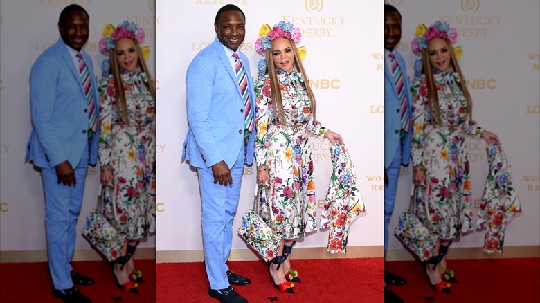 At the Kentucky Derby, Avery Johnson wears a light blue suit and multicolored stripe tie, while Cassandra Johnson wears a white dress with a colorful floral pattern and a floral crown.