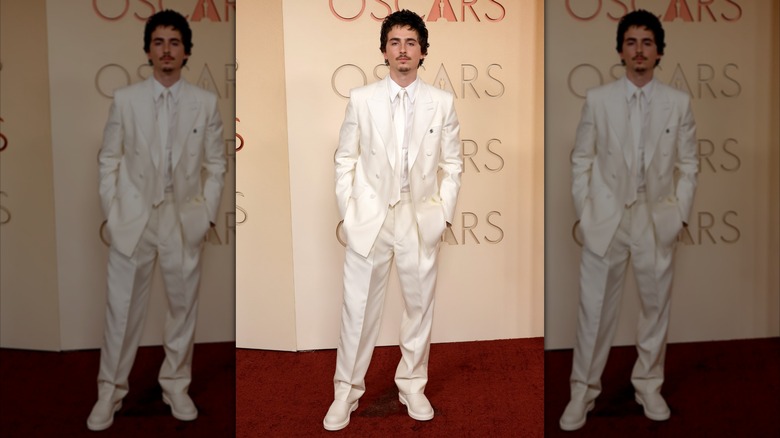 Timothee Chalamet posing on the red carpet for the 2026 Oscars in a white suit