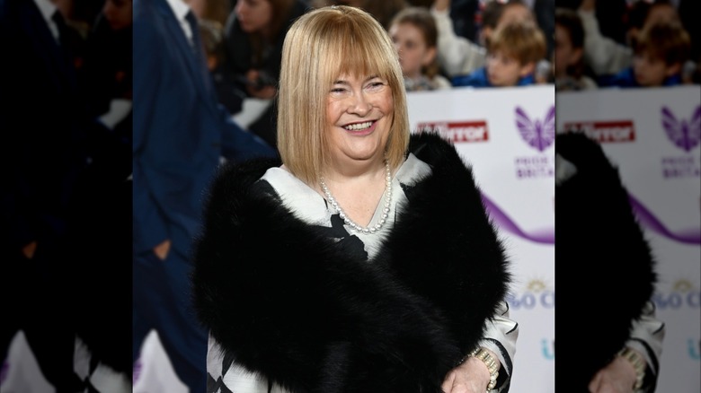 Susan Boyle smiling in a black fur stole.