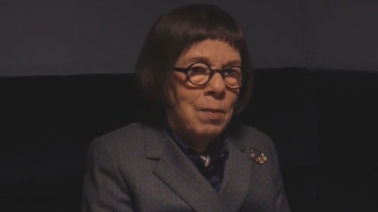 Linda Hunt, as Henrietta "Hetty" Lange, sports an amused expression.