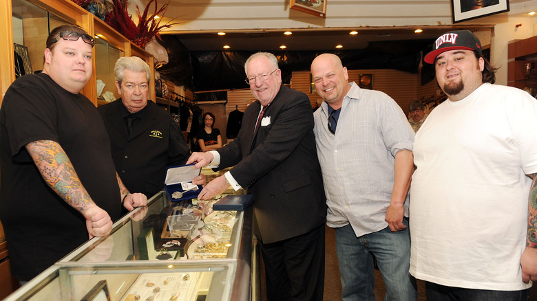 The cast of Pawn Stars posing around a display case.