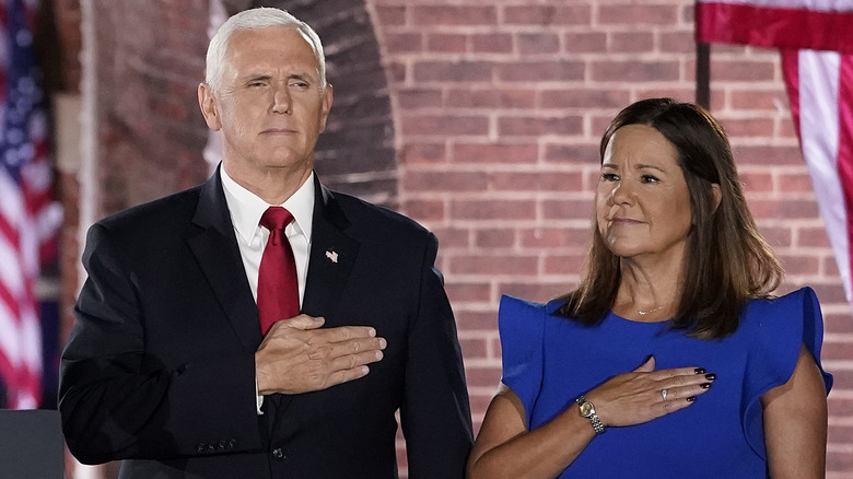 Mike and Karen Pence stand with their hands on their chests.