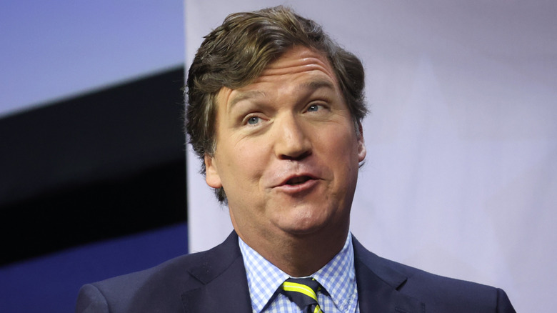 Tucker Carlson with palms facing upward