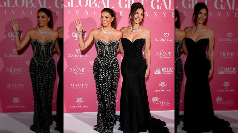 Dressed in a black number, Lauren Sánchez looks away from the camera, with one arm wrapped around a waving Eva Longoria.