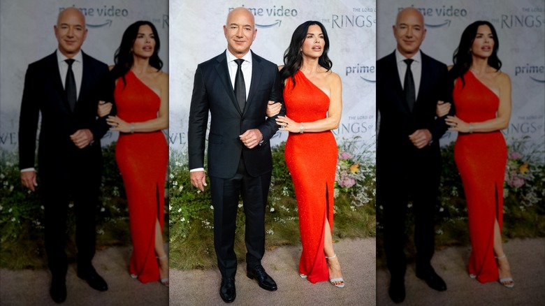 Dressed in an assymetrical red dress, Lauren Sánchez﻿ crosses her legs while holding Jeff Bezos' arm.
