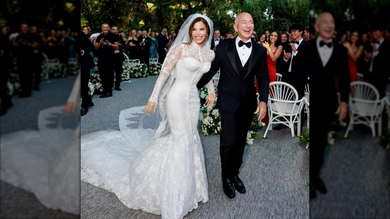 Wearing a buttoned-up, figure-hugging, white wedding dress, Lauren Sánchez smiles while walking with Jeff Bezos.