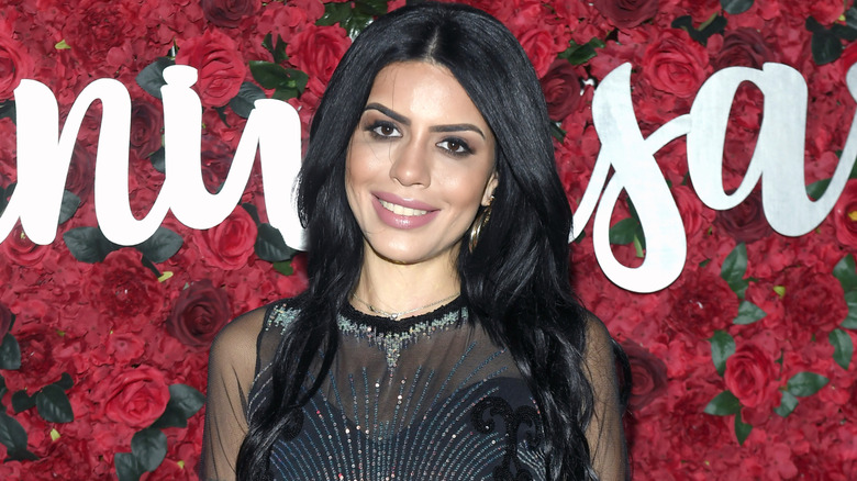 Larissa Lima smiles and poses in front of images of roses