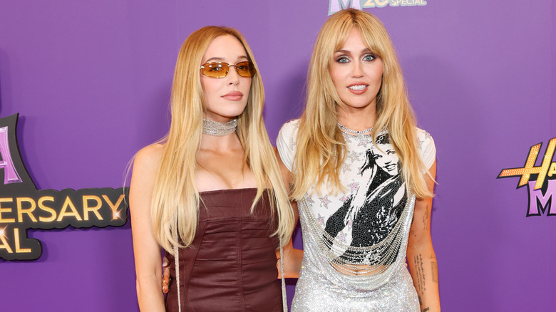 Miley Cyrus posing with her arm around Alex Cooper.