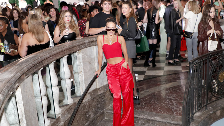 Sofia Franklyn posing in front of a crowd in a red bustier top and matching wide-leg pants.