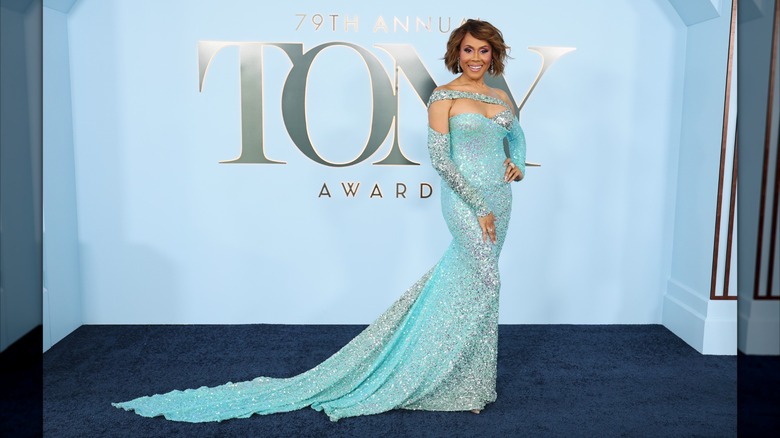 Deborah Cox posing on the blue carpet at the 2026 Tony Awards in an aqua dress.