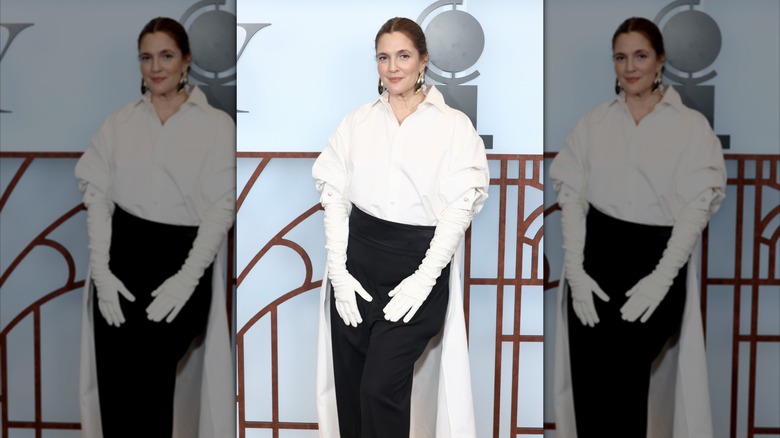 Drew Barrymore wearing white gloves, a white shirt, and black pants at the 2026 Tony Awards.