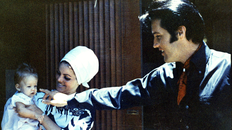 Lisa Marie, Priscilla, and Elvis Presley posing for cameras